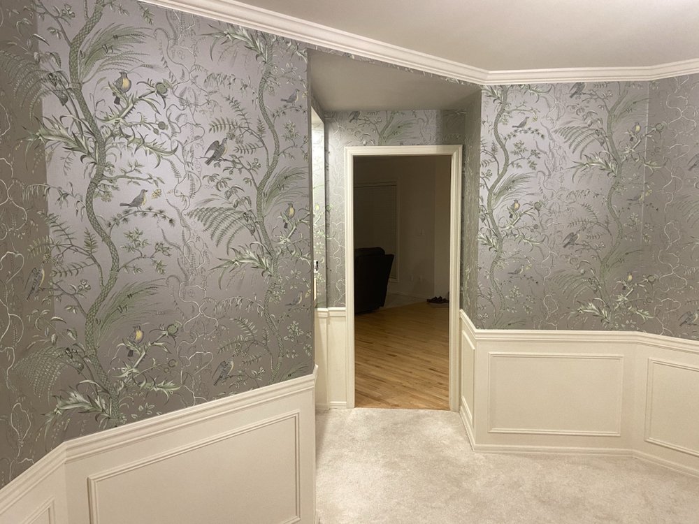 Chinoiserie bird and botanical wallpaper above wainscoting in a luxury hallway, installed by Mancini Wallpapers