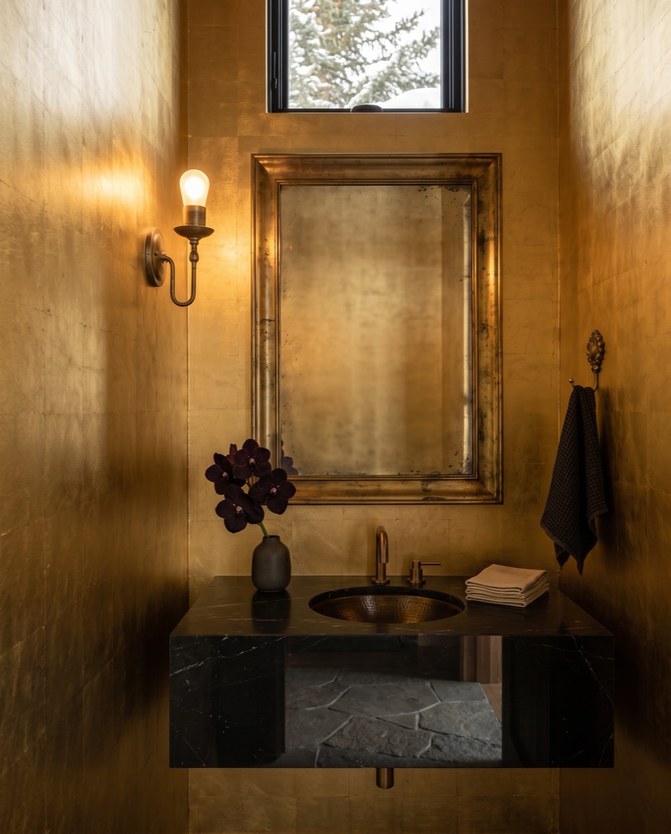Gilded gold-leaf wallcovering in a powder room with a brass sconce and marble vanity, Deer Valley, Utah