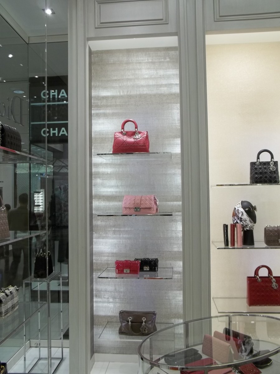 Silver textured wallcovering behind a luxury retail display, installed by Mancini Wallpapers